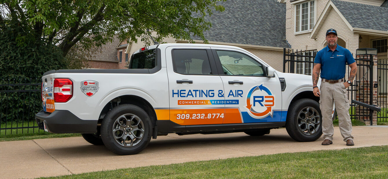 R3 Heating & Air technician standing by an R3 service truck outside a residential home in Iowa, ready to provide HVAC maintenance and repair.